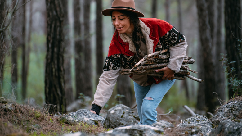 Lady wearing a fure lined jacket gathers firewood 