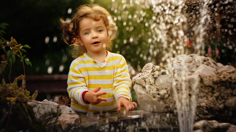 Little girl playing with water in fountain