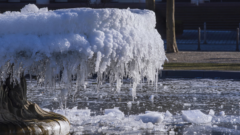 frozen fountain with snow and ice hanging from it