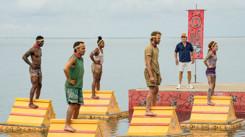 Survivor contestants standing on floating platforms on water
