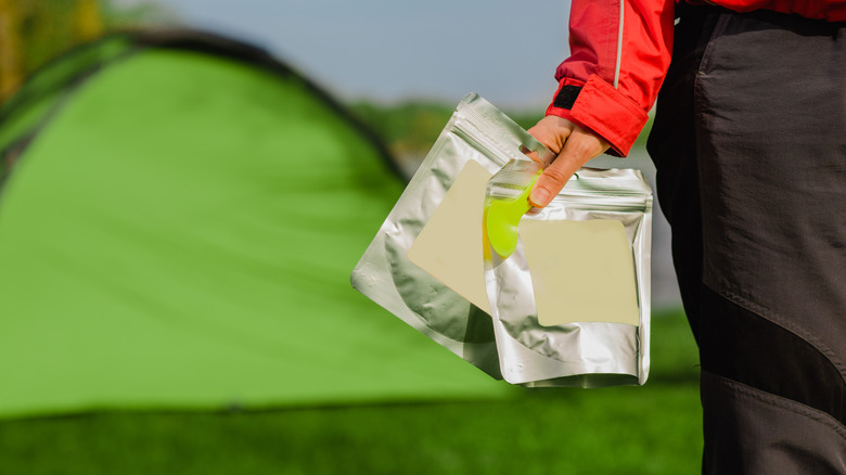 Camper holding two packets of freeze dried hiking food