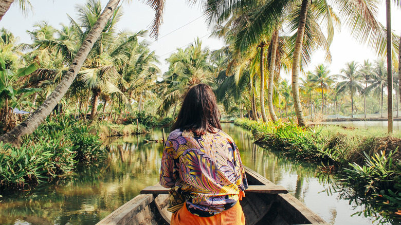 Woman in boat surrounded by palm trees