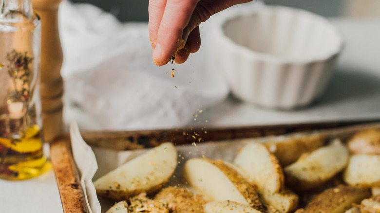 Hand sprinkling herbs on potatoes