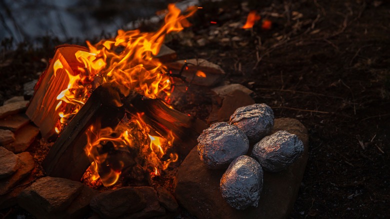 Foil-wrapped potatoes on campfire