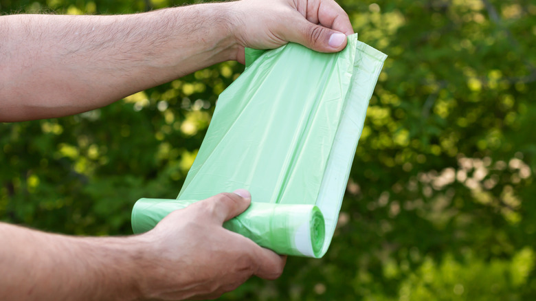 Person unrolling green plastic bag