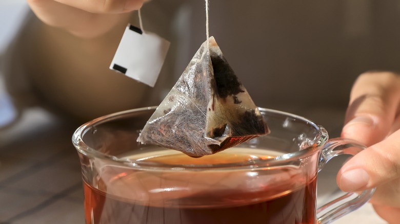 Person removing a tea bag from mug