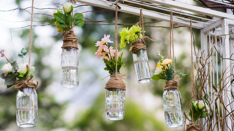 Glass jars with flowers hanging from trellis