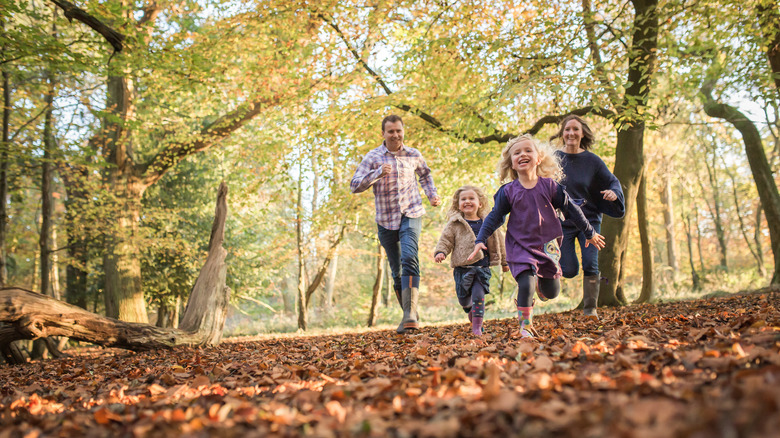 Family running through autumn woods