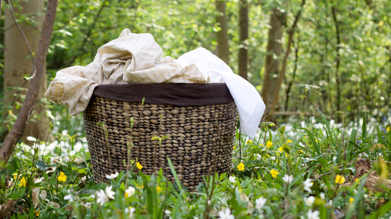 A laundry basket full of clothes sitting outside in a field of wildflowers