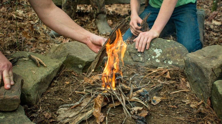 Kid and adult starting a campfire