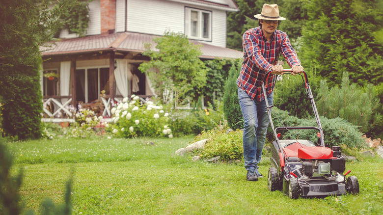 man mowing lawn beside a house