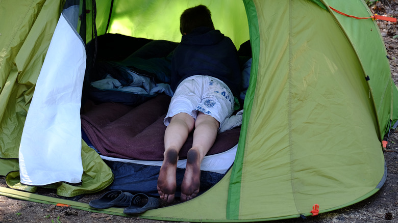 Child with dirty feet sticking out of tent