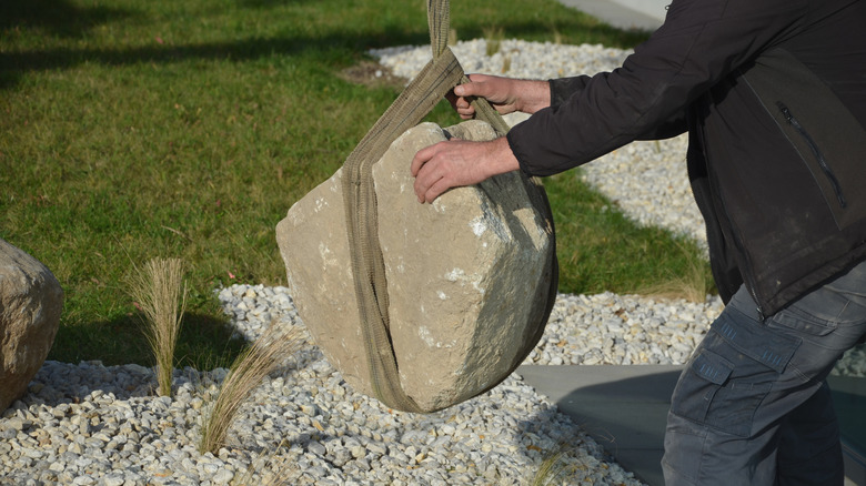 Person picking up granite boulder for project