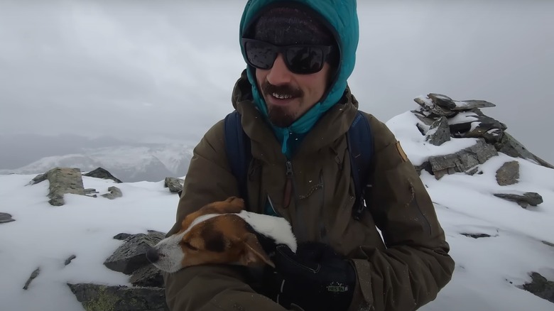 Foresty Forest seated on snowy mountain with dog nuzzled in lap