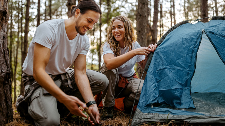 Happy man and woman setting up tent