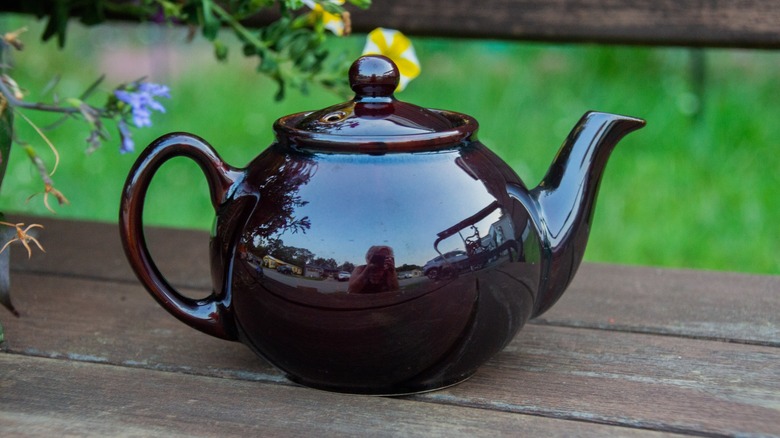 Black tea pot on picnic bench outside