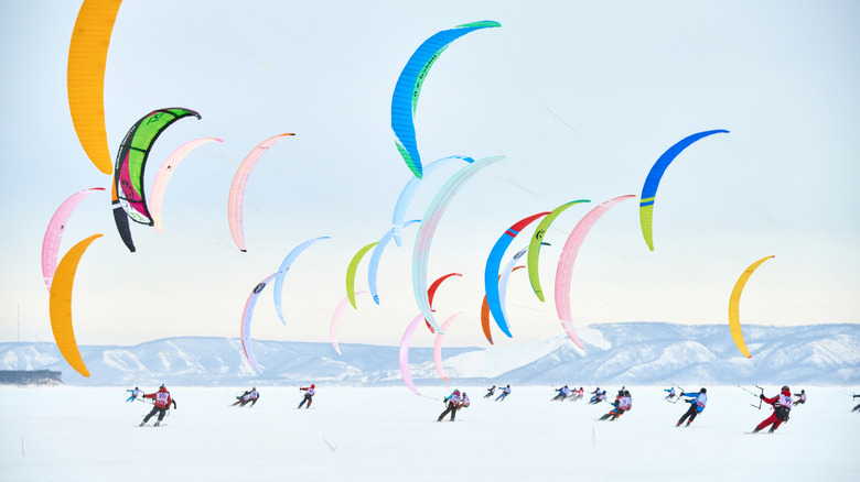 Snowkiters with colorful kites in the air above snow