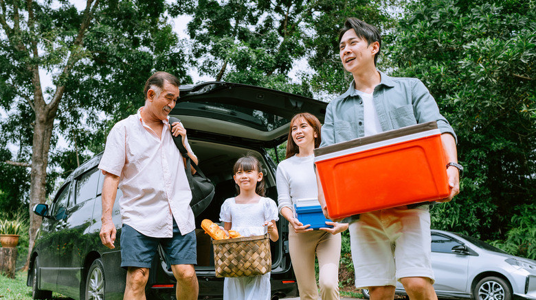 Family carrying cooler and picnic baskets outside