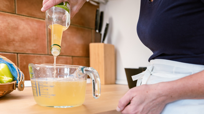 Woman pouring vinegar into measuring bowl