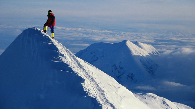 Person standing on a snow-covered peak of Mt. Denali