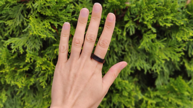 Person wearing RingConn, hand in front of trees