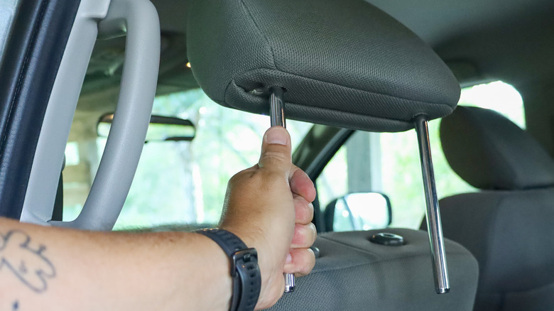 Hand removing headrest from carseat