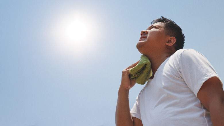Man frustrated due to heat, looking up at sun