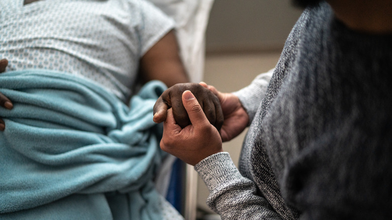 Person holding patient's hand in hospital