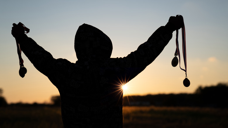 Silhouette of person holding medals