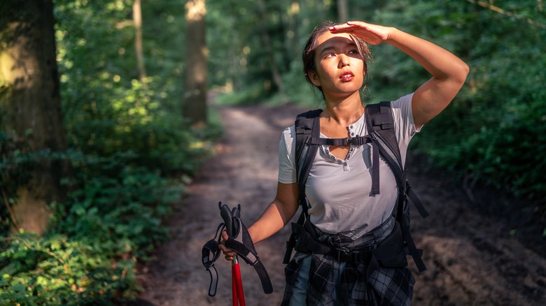 Woman shielding sun from eyes in forest