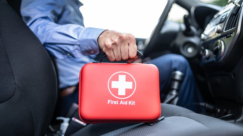 Man holding first aid kit in a car