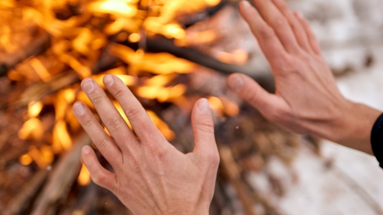 Warming hands in front of winter fire 