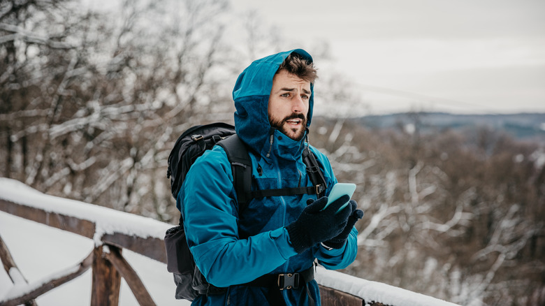 Hiker lost in the snow, holding phone