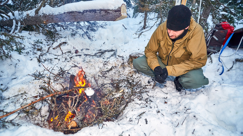Winter camper melts snow in a fire 