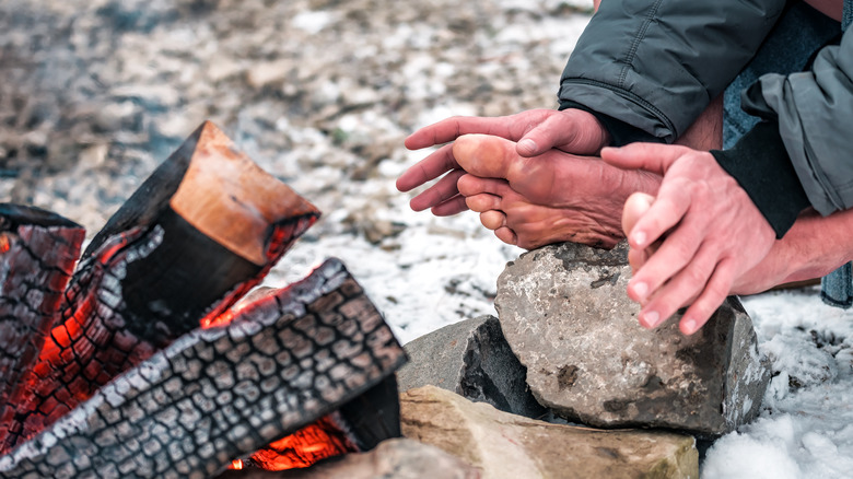 Man warming cold feet by a fire 