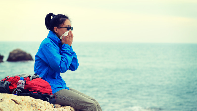 Hiker seated on rock and blowing nose