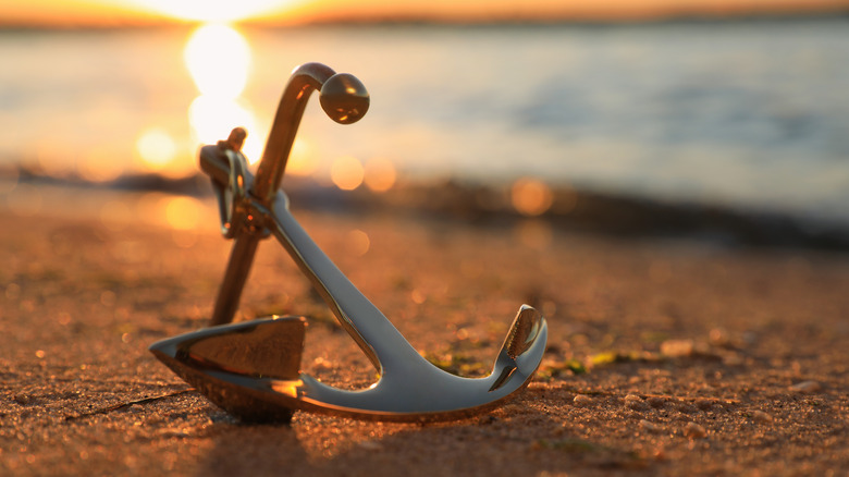 Metal anchor on shore during sunset