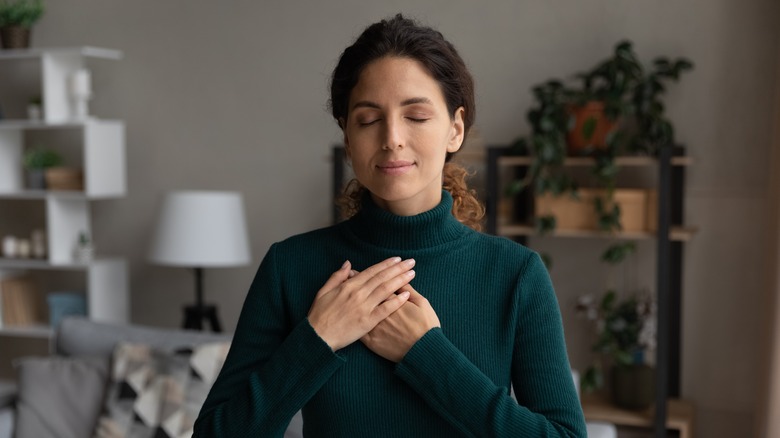 Calm woman pressing hands to chest