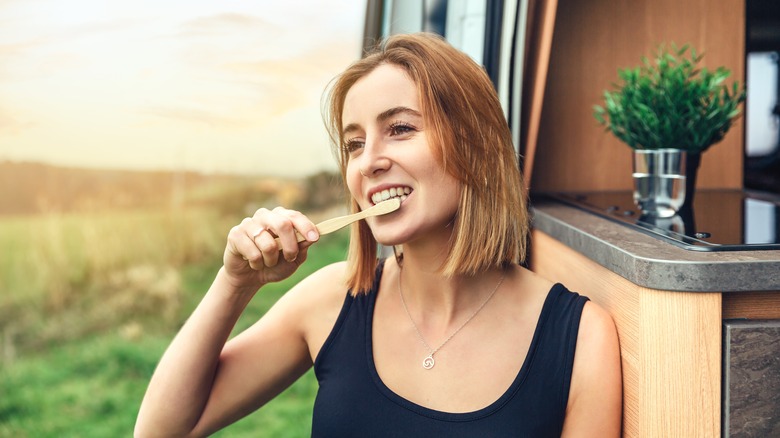 Woman brushing teeth outside RV