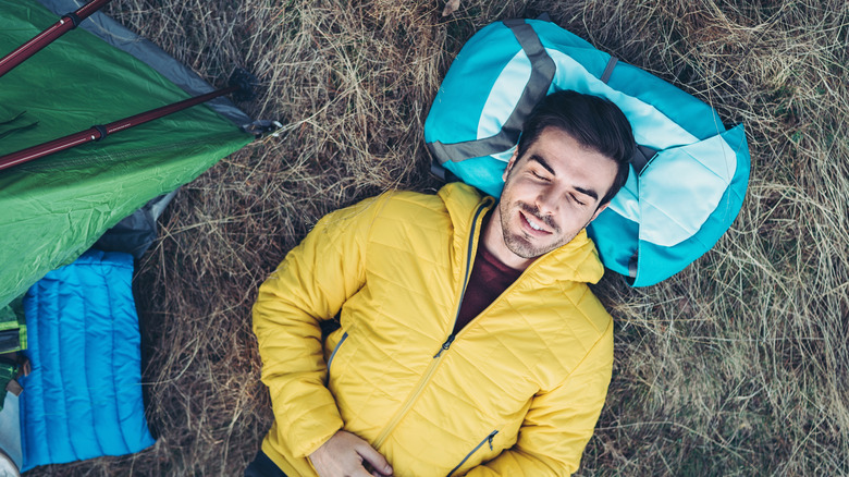 Male camper resting on backpack
