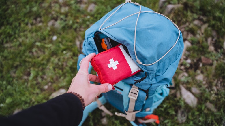 Person pulling first aid kit out of backpack