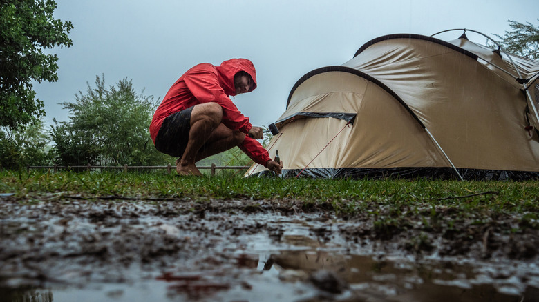 Camper fixing tent on rainy day