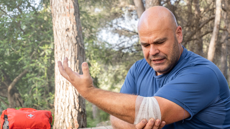 Man bandaging cut on elbow