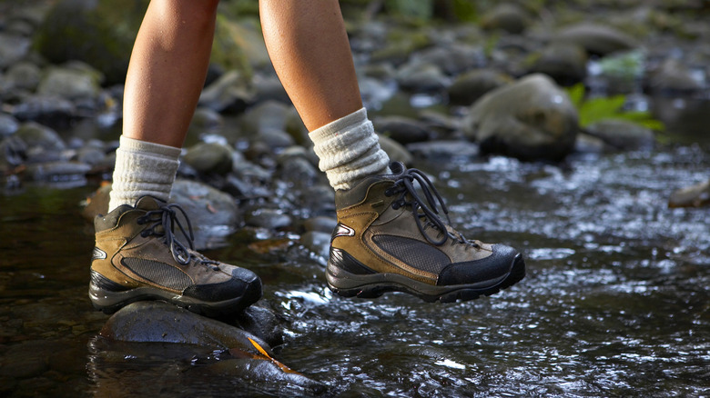 Someone in hiking boots walking across a stream