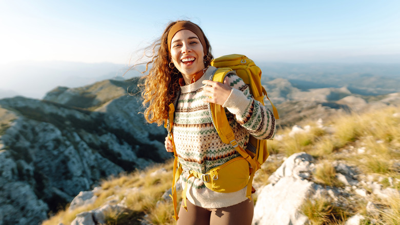 Woman with backpack going hiking and smiling