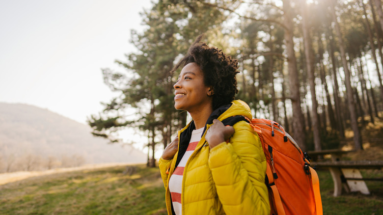 Woman smiling, wearing backpack and layers for hike