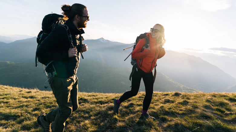 Two people hiking with backpacks and laughing