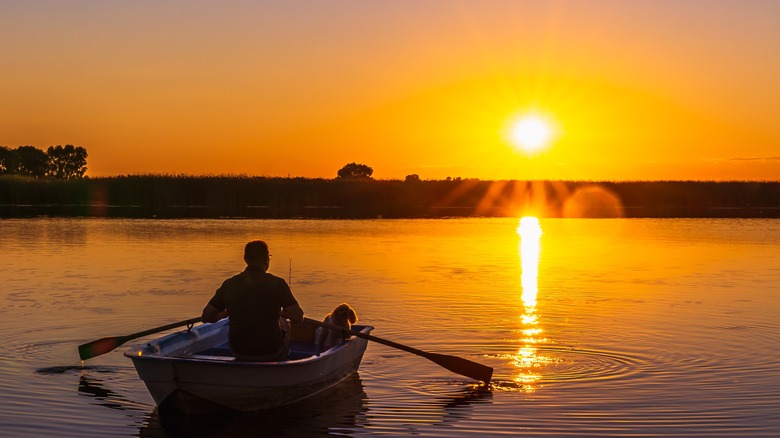Man fishing in a boat at sunset