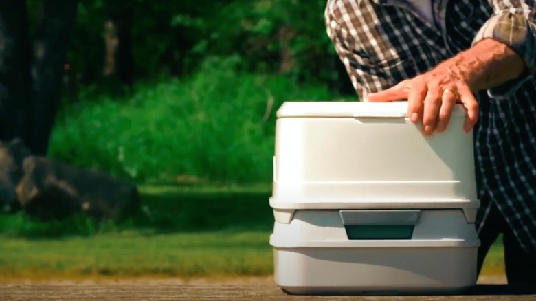 Man holding compact/cassette toilet on table