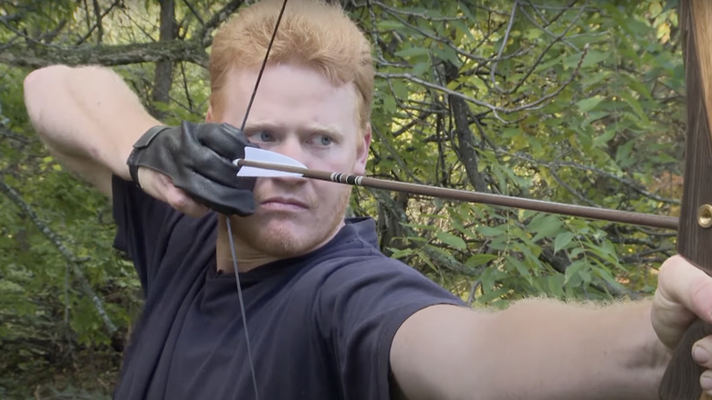 Man nocking an arrow in the woods